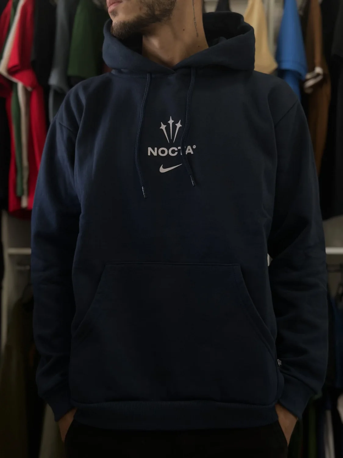 O moletom 3 cabos Nike Nocta vestido, na frente das araras da loja