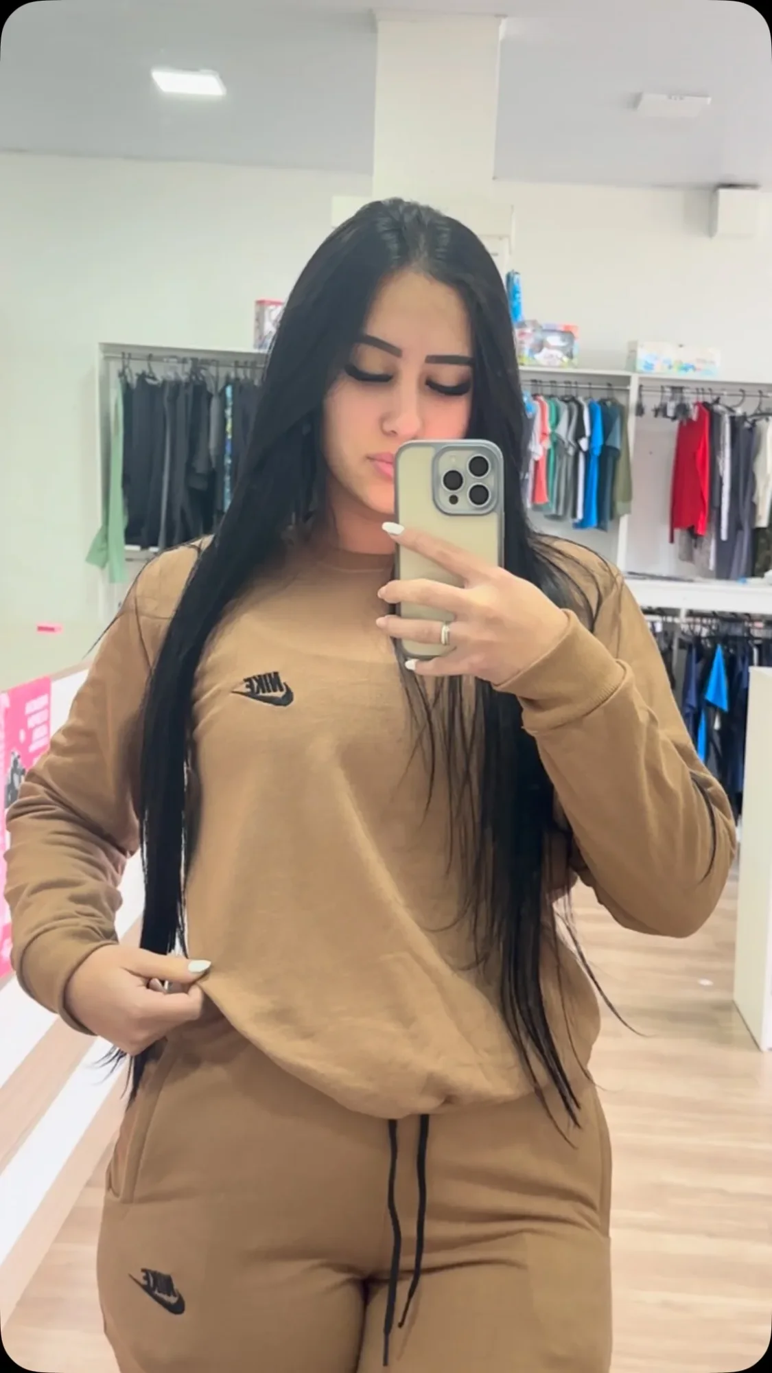 Dentro da Prime Center: as araras de roupa e uma cliente vestindo o conjunto de moletom Nike